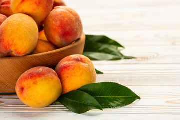 Peaches with leaves close-up on a white wooden table