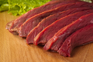 sliced fresh meat on a board with salad