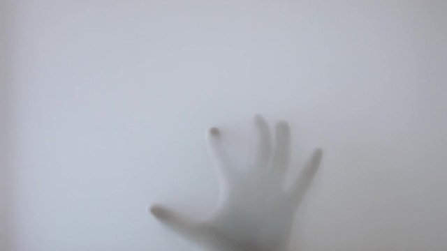 The hand slowly crawls like a spider across the glass window of the bathroom.