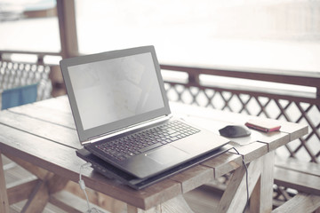 Wooden table on the veranda office laptop Internet modern gadget copy space.