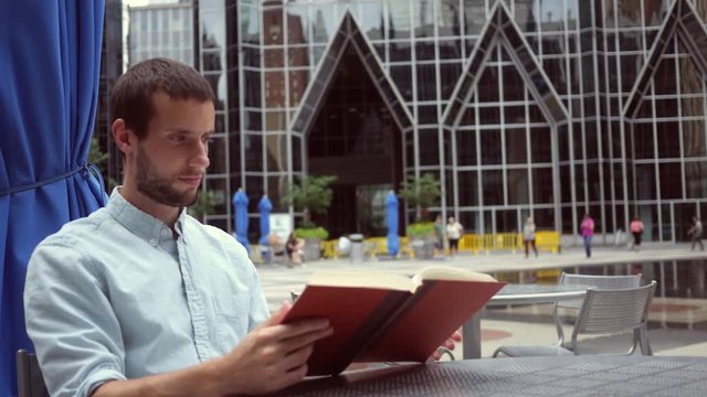 A Man reads a book near an urban park area