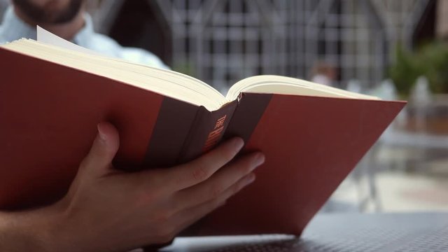 A Man reads a book near an urban park area ALT