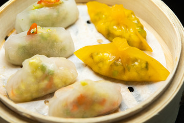 Closeup of colorful dim sum in a steamer wooden basket