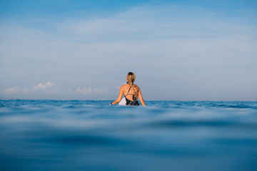 Alone surfer woman in swimwear with surfboard. Woman with surfboard in ocean.