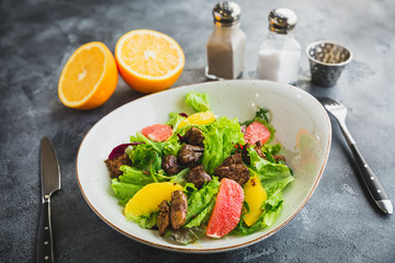 Tasty fresh salad with citrus, lettuce and chicken liver in a plate. Diet food.