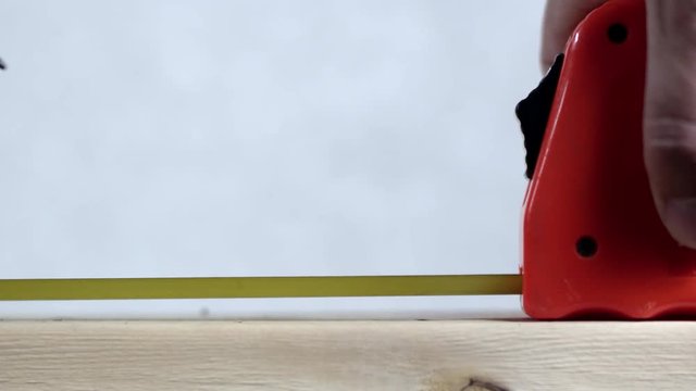 Tape measurer sliding across wood and pencil makes a mark then tape slides back the other way.