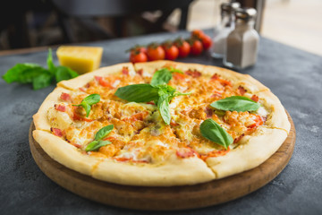 Italian pizza with bacon, cheese and tomato on dark table. Closeup view. Delicious food