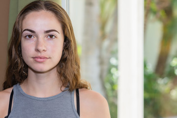 Young woman portrait in casual clothes with window to outdoors in background and copy space