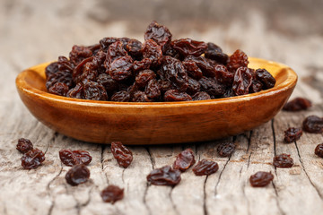 Raisins in a wooden bowl on the old wooden table