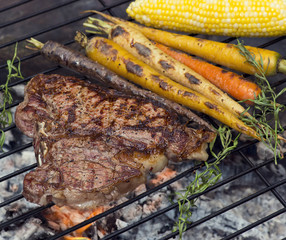 T bone steak cooking on fire with vegetables