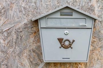 A gray mailbox on a wooden wall.