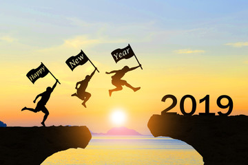 Happy New Year 2019 Men jump over silhouette mountains and sun