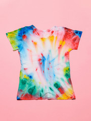 T-shirt painted in tie dye style on a pink background. Flat lay. Pastel color.