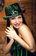 brunette girl in an elf costume in a green corset and short skirt in green and white striped Golf in a green cylinder with a pot of gold, the concept of St. Patrick's day for the new year