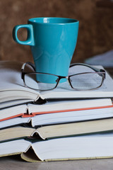 A stack of open books, glasses and a Cup of coffee. Library. Study. Reading