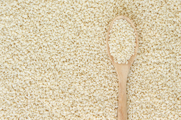 white sesame seeds in spoon on white backgroud