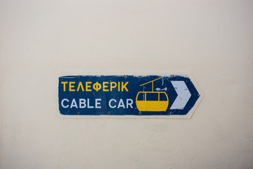 Blue and yellow sign for cable car in Santorini, Greece