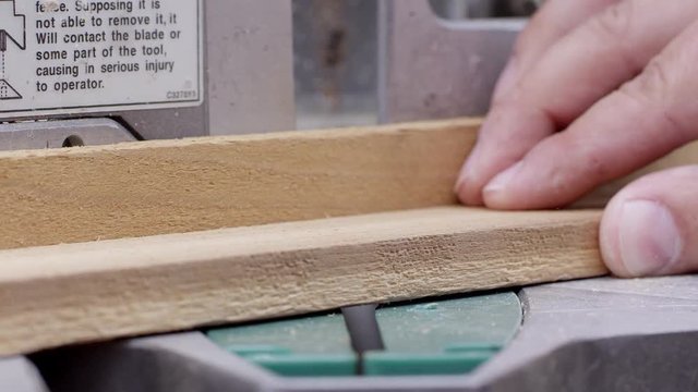 Close up view of miter saw cutting a board and an angle as the wood pieces are removed.