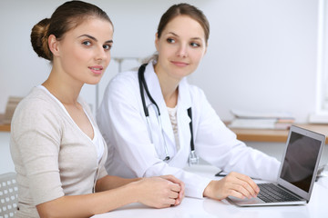 Doctor and patient having a pleasure talk while sitting at the desk at hospital office. Healthcare and medicine concept