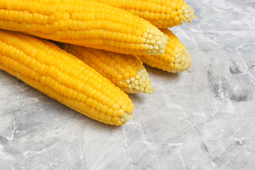 Ripe boiled corn on a gray concrete table, top view.