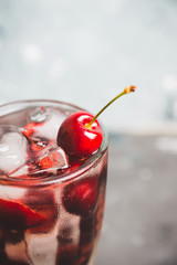 Cold cherry cocktail with ice and strong alcohol. Selective focus.