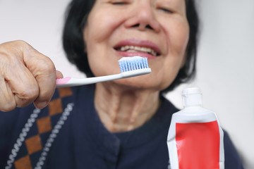 Asian elderly woman trying use toothbrush ,hand tremor . Dental health