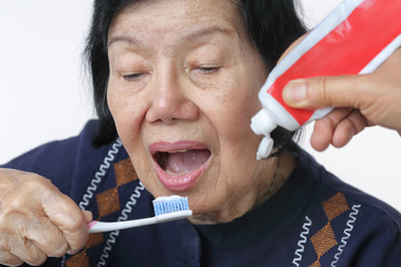 Asian elderly woman trying use toothbrush ,hand tremor . Dental health
