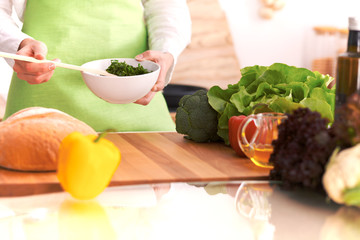 Close Up of human hands cooking vegetable salad in kitchen on the glass table with reflection. Healthy meal, and vegetarian food concept