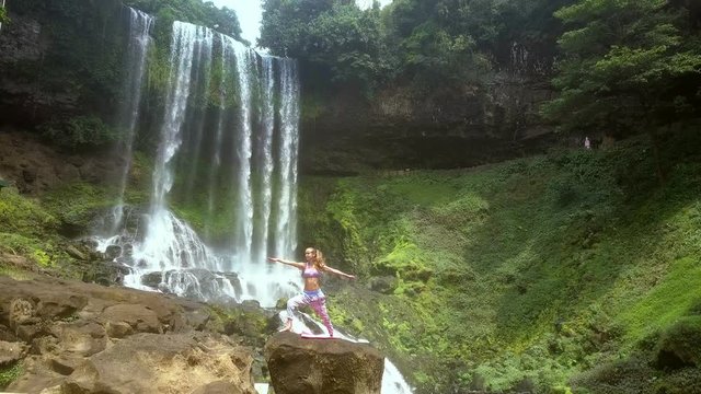 drone removes from blonde lady with ponytail by waterfall