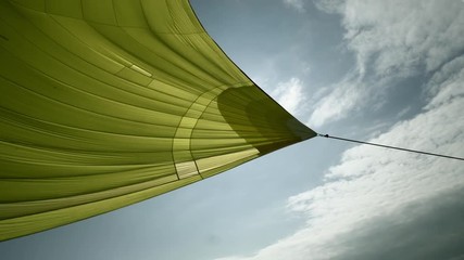 Yellow sails of yacht on background of blue sky and white clouds. Regatta and ocean as a lifestyle.