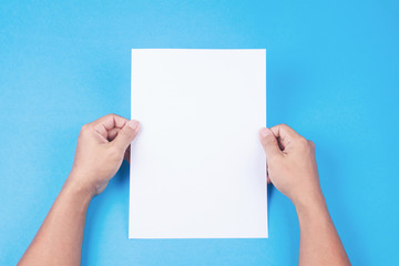 Blank brochure with blank in hand on blue background. Mockup for design
