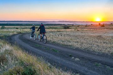 Fototapeta na wymiar father and son ride a bike in the country on the field in the evening