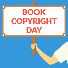 BOOK COPYRIGHT DAY. Hand holding wooden sign