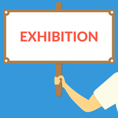 EXHIBITION. Hand holding wooden sign