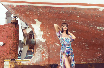 Beautiful, sensual and sexy fashion model posing in front of old rusty boat.