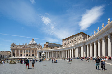Obraz premium Statues on the colonnades and tourists in front of a fountain in St Peter's square