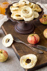 Naklejka na ściany i meble Dessert. Dried apple rings in a round old vase, next to fresh apples on a brown wooden board. 