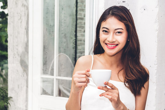 Beautiful young woman relaxing holding a cup of coffee in cafe