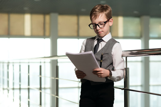 boy in a business dressed in glasses, standing in the office, with documents