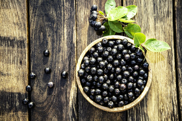chokeberry in a wooden bowl in the morning garden