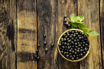 chokeberry in a wooden bowl in the morning garden