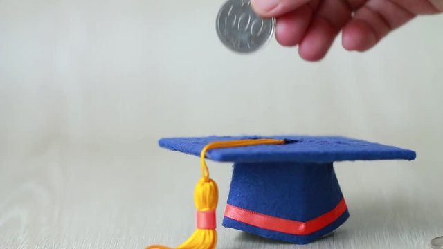 Student hand dropping investing South Korean won money coin to Graduation fund for save moneys in studying abroad. Education savings and investment ideas