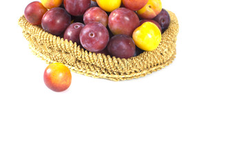 Plum fruit in straw wicker bowl isolated on white