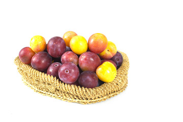 Plum fruit in straw wicker bowl isolated on white