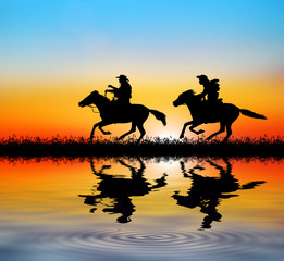 silhouette Cowboy riding a horse and water reflection on sunrise