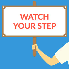 WATCH YOUR STEP. Hand holding wooden sign