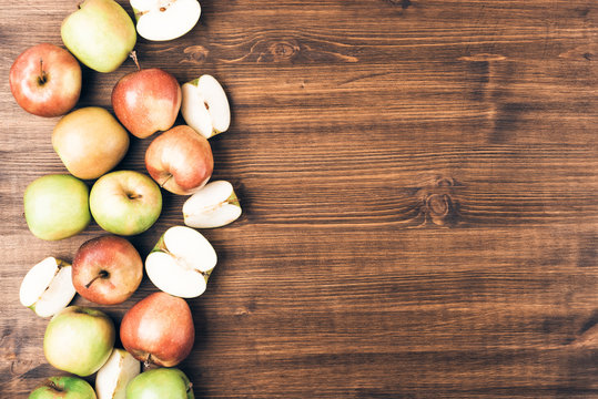 Sweet juicy red and green apples with yellow leaves on wooden background. Free copy space for text. Top view, flat lay