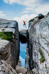 Man jumping over Kjeragbolten Travel in Norway Kjerag mountains extreme vacations adventure tourist...