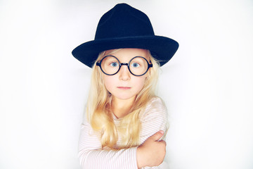 Cute little blonde girl wearing a stylish hat and glasses