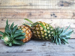 Fresh ripe pineapple just picked up from the garden on brown wooden table.